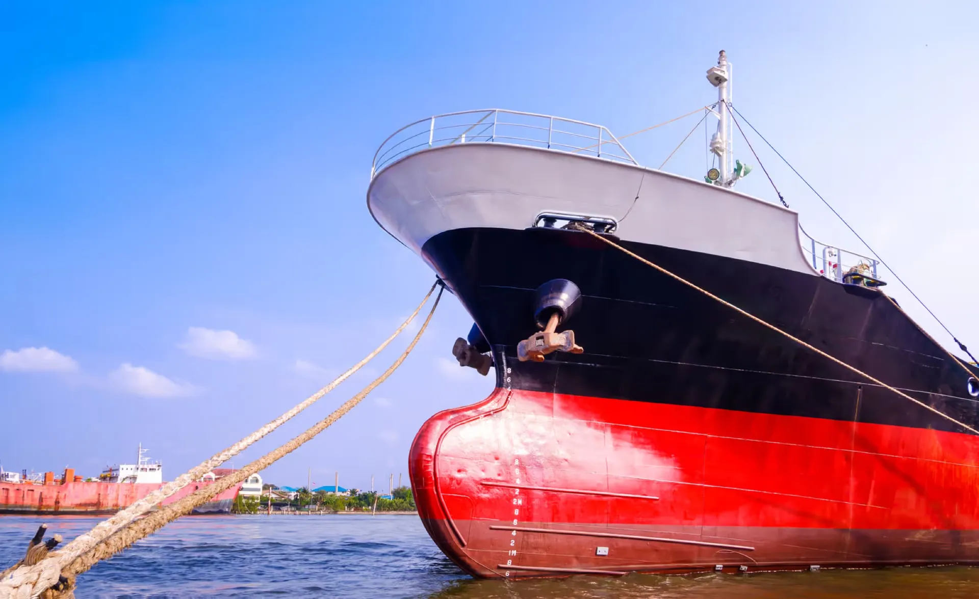 Bow of a cargo vessel with a red hull and white superstructure